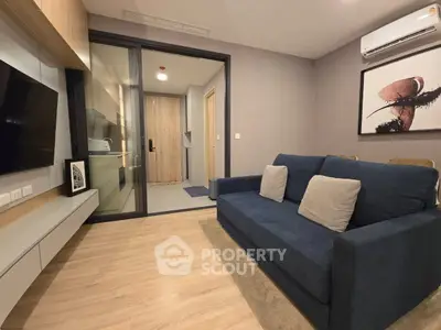Modern living room with stylish decor and cozy blue sofa, featuring a sleek wall-mounted TV and elegant artwork.