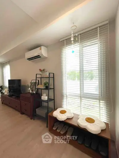 Charming living room with modern decor, air conditioning, and ample natural light from large windows.