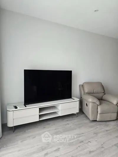 Modern living room with sleek TV stand and comfortable recliner on stylish wooden flooring.
