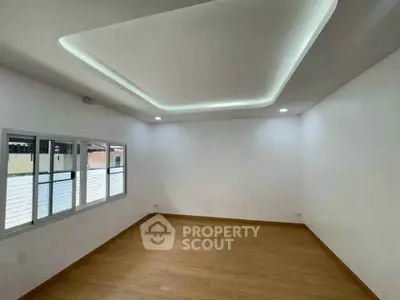 Spacious modern room with wooden flooring and stylish ceiling lighting, perfect for versatile interior design.