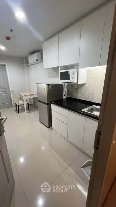 Modern compact kitchen with sleek white cabinets and stainless steel appliances