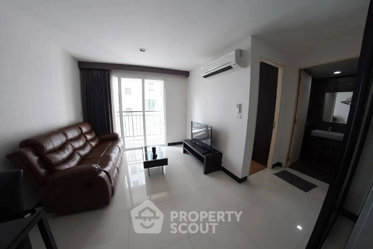 Modern living room with leather sofa, TV, and balcony access in a stylish apartment.