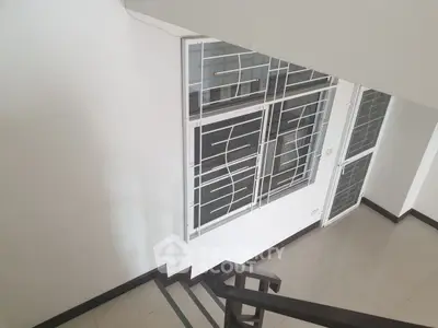 Modern staircase with sleek metal railing and large window in a contemporary home