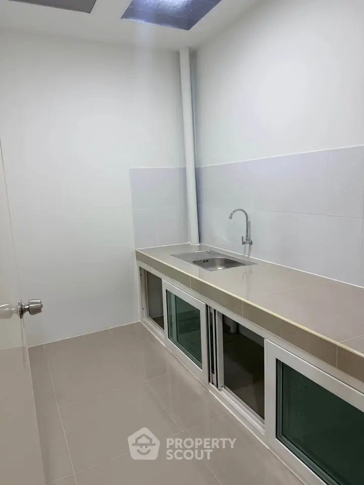 Modern minimalist kitchen with sleek countertops and built-in sink, ideal for compact spaces.