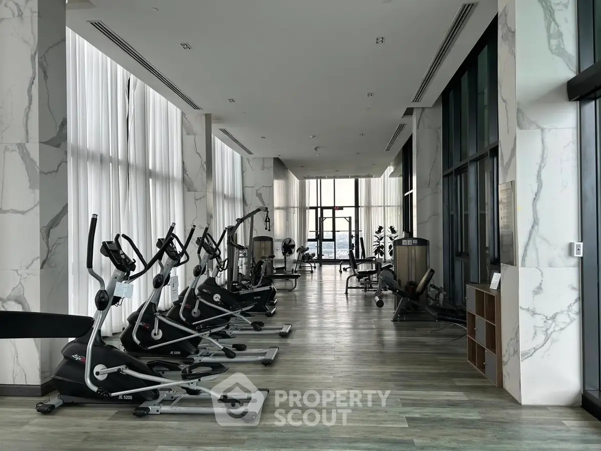 Luxurious gym with modern fitness equipment and floor-to-ceiling windows in a high-end building.