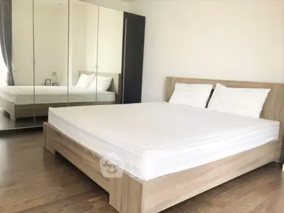 Spacious bedroom with mirrored wardrobe and wooden flooring