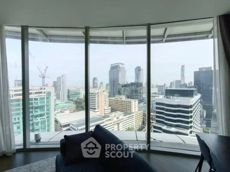 Stunning panoramic city view from modern high-rise apartment with floor-to-ceiling windows.