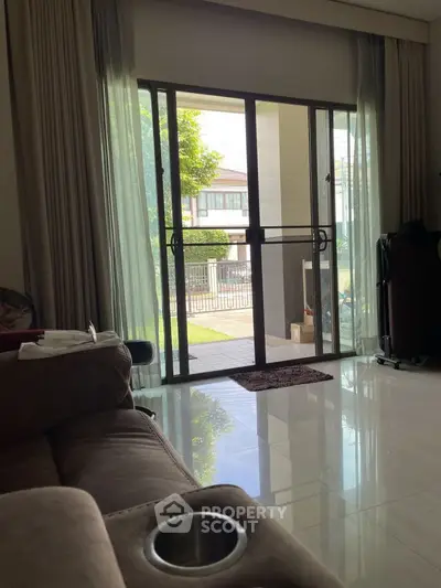 Spacious living room with sliding glass doors opening to a garden view, featuring modern furniture.