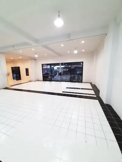 Spacious open-plan interior with modern tiled flooring and large windows.