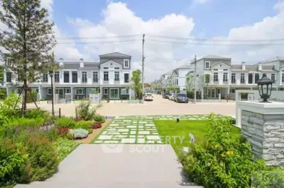 Charming suburban neighborhood with modern townhouses and lush gardens under a clear blue sky.