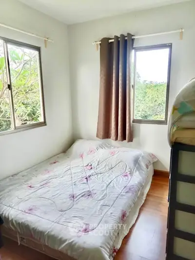 Cozy bedroom with natural light and garden view, featuring a comfortable bed and wooden flooring.