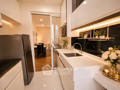 Modern kitchen with sleek white cabinetry and elegant lighting, featuring a double sink and stainless steel appliances.