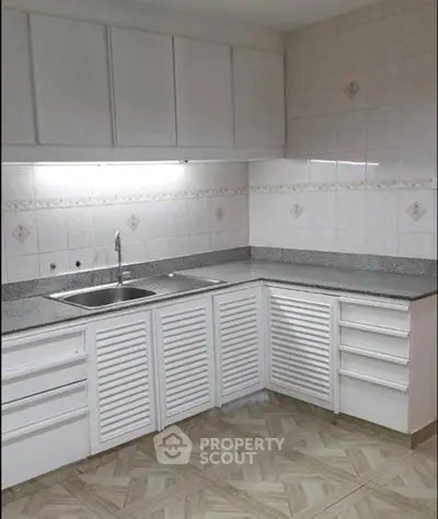 Modern kitchen with sleek white cabinets and granite countertops in a stylish apartment.