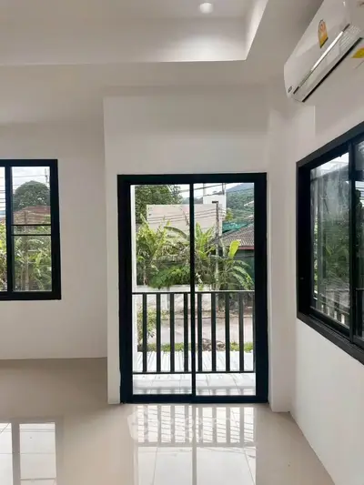 Bright living room with large windows and balcony view, showcasing modern design and natural light.