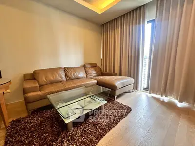 Modern living room with leather sofa and glass coffee table, featuring floor-to-ceiling curtains.