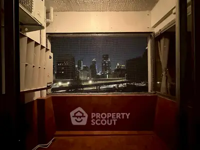 Cozy balcony with city skyline view at night, perfect for relaxation.