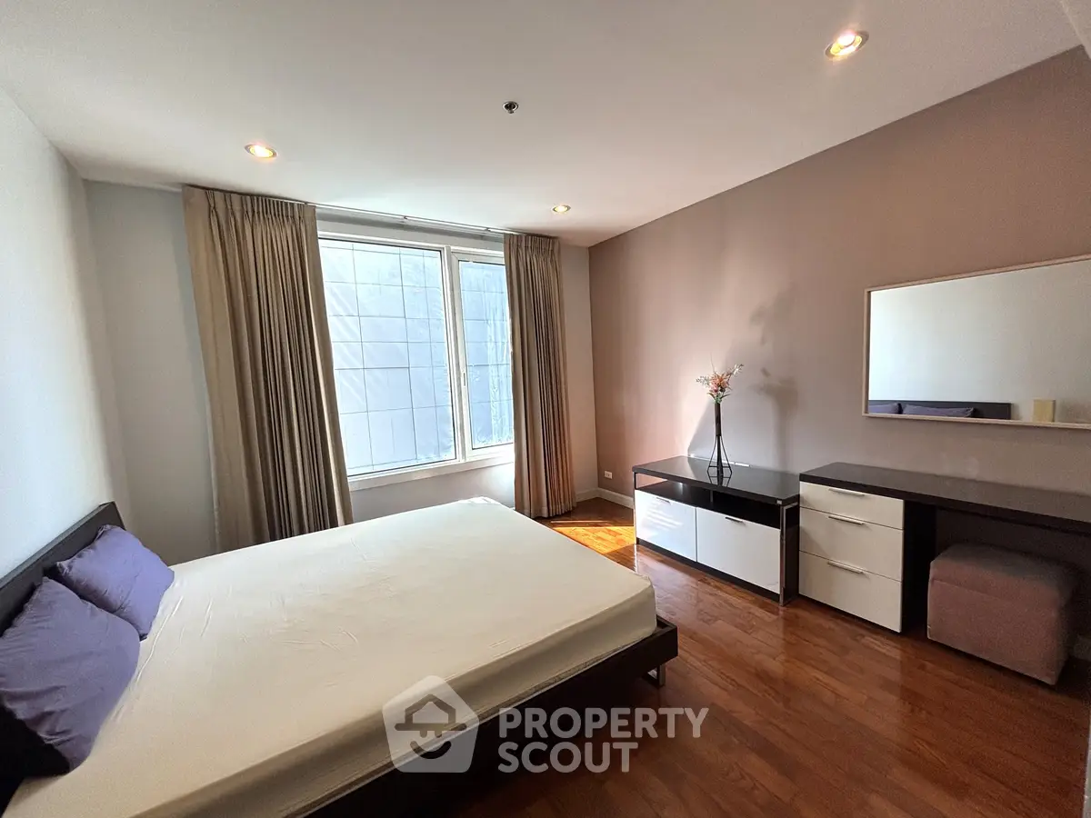 Spacious bedroom with natural light and modern furnishings in a stylish apartment.