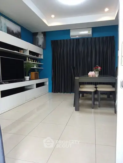 Modern living room with sleek furniture and dining area, featuring stylish decor and bright lighting.