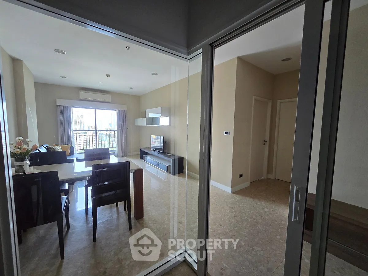 Spacious modern living room with dining area and large windows offering city views.