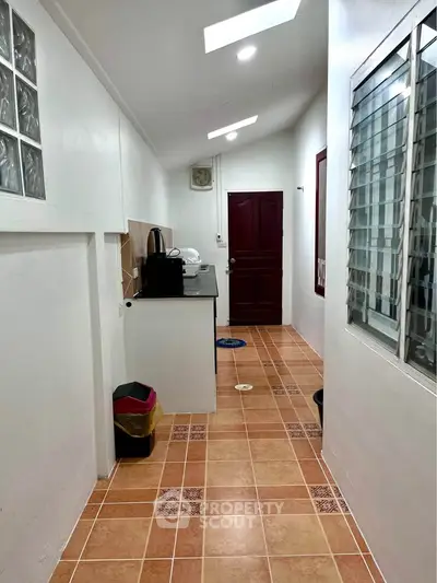 Charming narrow hallway with tiled floor and modern appliances, perfect for compact living spaces.