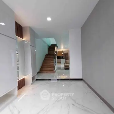 Elegant modern interior with marble flooring and stylish staircase leading to a cozy living area.
