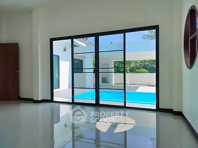 Spacious living room with pool view and large glass doors in modern home