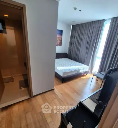 Modern bedroom with wooden flooring and large window, featuring a comfortable bed and stylish decor.