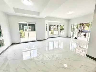 Spacious modern living room with large windows and glossy tiled floors
