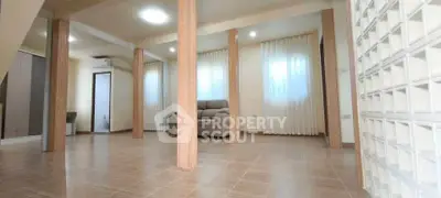 Spacious living room with modern design and natural light, featuring a cozy sofa and elegant columns.