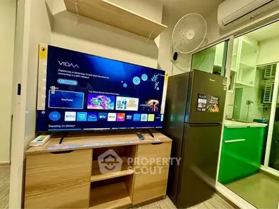 Modern living room with smart TV and sleek kitchen appliances in a cozy apartment.
