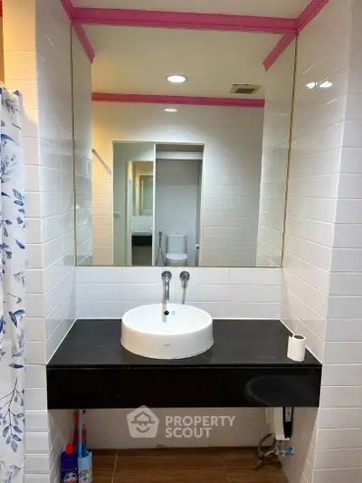 Modern bathroom with stylish sink and large mirror, featuring elegant tile design and contemporary fixtures.