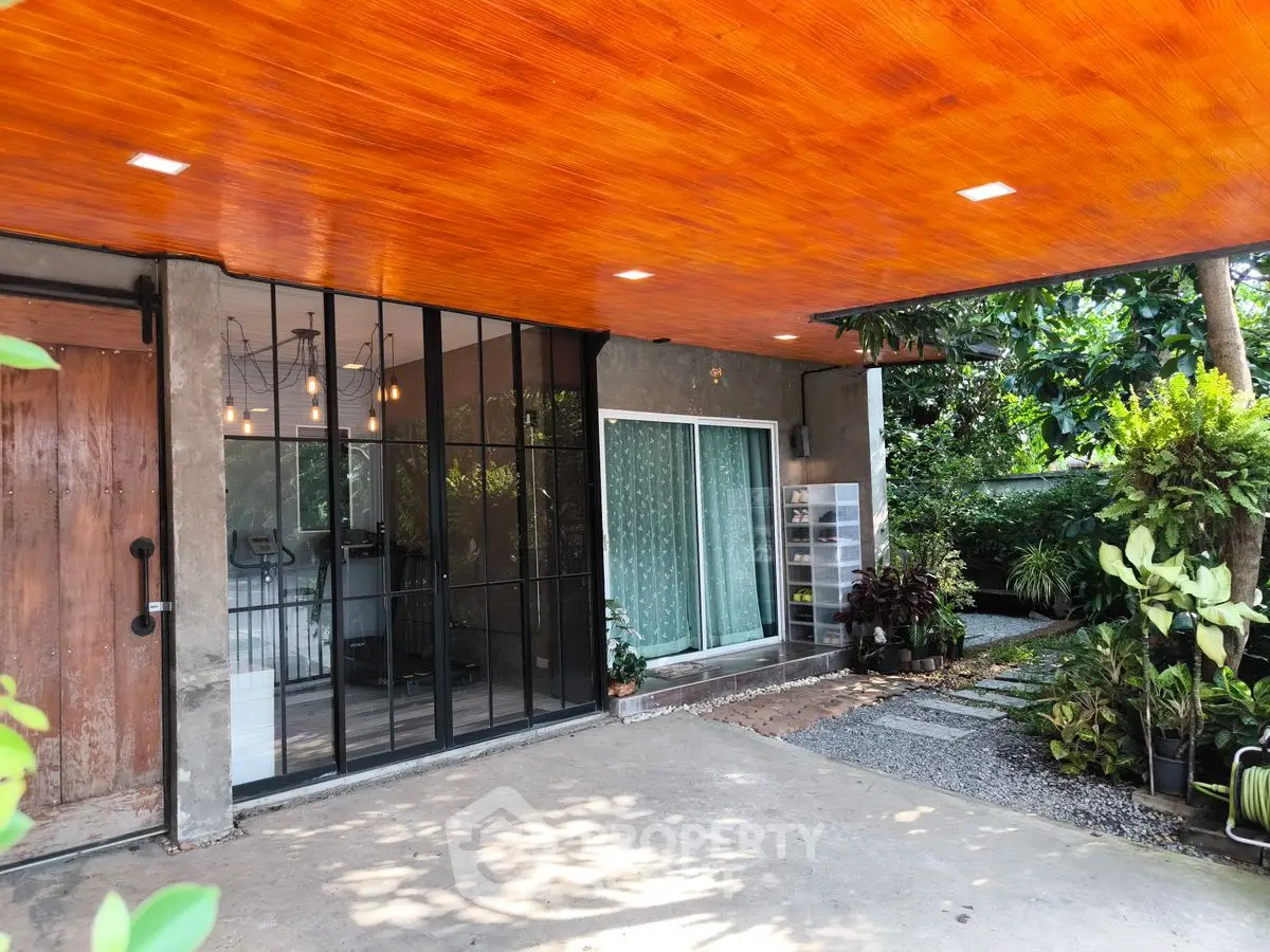 Modern home exterior with wooden ceiling and lush garden