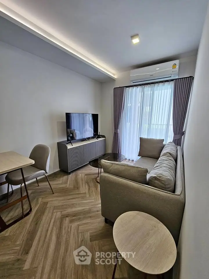 Modern living room with stylish furniture and natural light, featuring a cozy sofa and sleek TV setup.