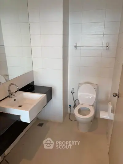 Modern bathroom with sleek fixtures and minimalist design, featuring a white sink and toilet.