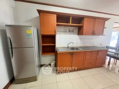 Spacious kitchen with wooden cabinets and modern fridge in a cozy apartment.