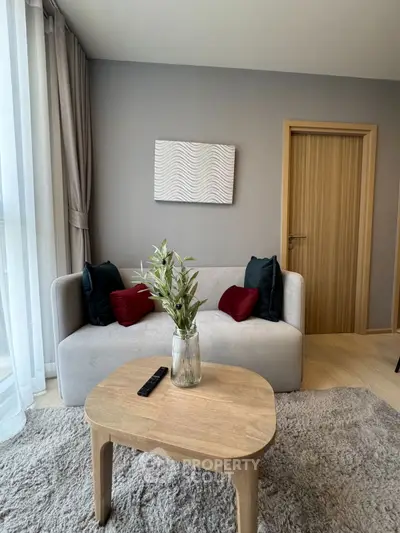 Modern living room with cozy sofa, stylish decor, and natural light from large windows.