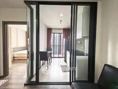 Modern apartment interior with glass partition, sleek kitchen, and city view balcony.