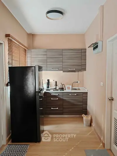 Modern kitchen with sleek cabinets and black fridge in cozy apartment
