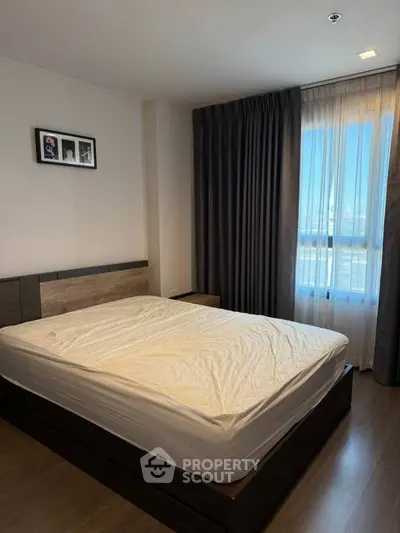 Spacious bedroom with large window and modern decor in a stylish apartment.