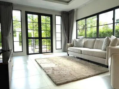 Elegant living room with large windows and plush sofa, offering a bright and inviting atmosphere.
