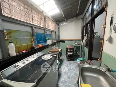 Charming kitchen with washing machine and open layout, featuring natural light and tiled flooring.