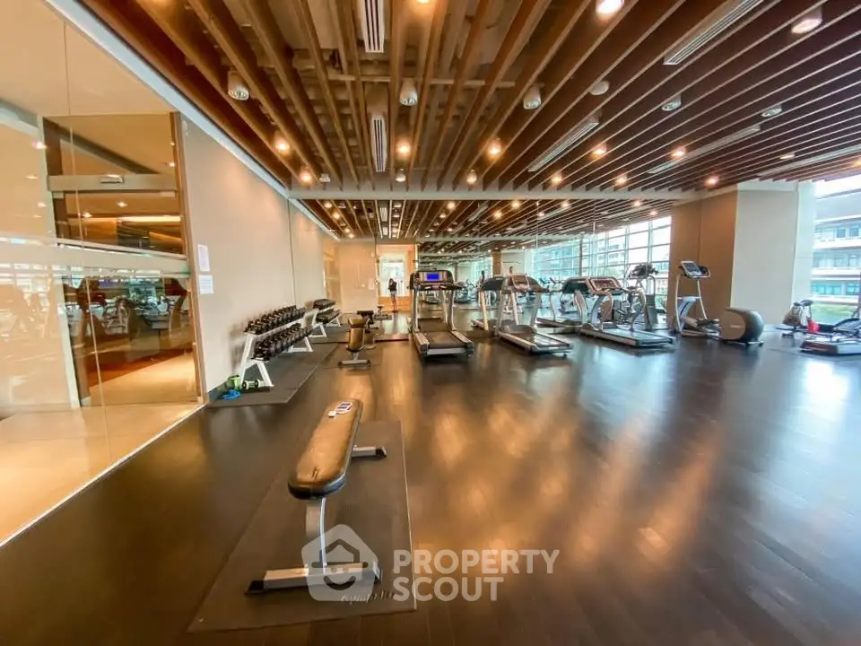 Spacious modern gym with state-of-the-art equipment and panoramic windows in luxury building.