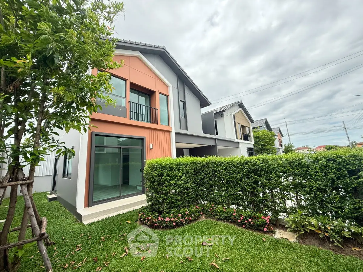 Modern two-story house with lush garden and large windows, perfect for family living.