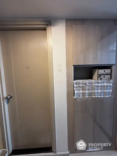 Compact storage area with built-in cabinets and laundry space in modern apartment.