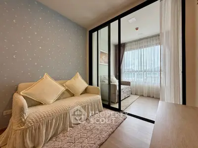 Charming living room with cozy sofa and elegant sliding glass doors leading to a bright bedroom.