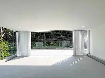 Spacious modern balcony with glass railing and lush garden view, perfect for relaxation and outdoor enjoyment.