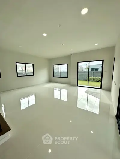Spacious modern living room with large windows and glossy white flooring