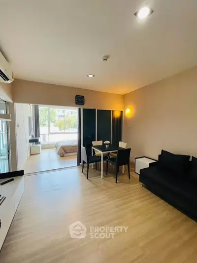 Modern open-plan living room with dining area and view into bedroom