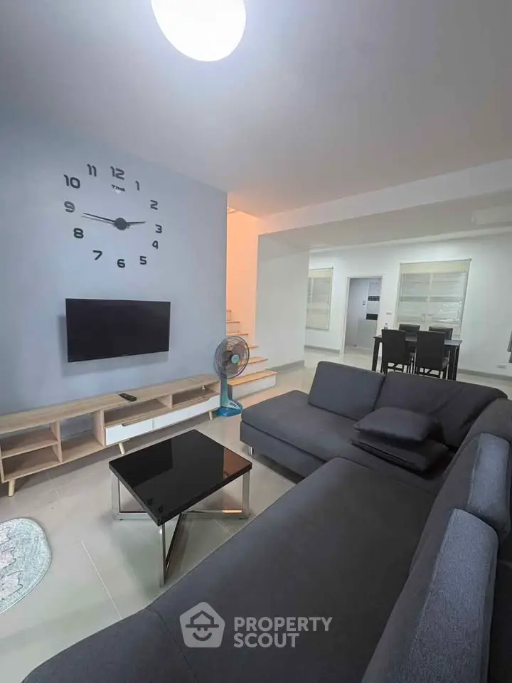 Modern living room with stylish furniture and wall clock, perfect for relaxation.
