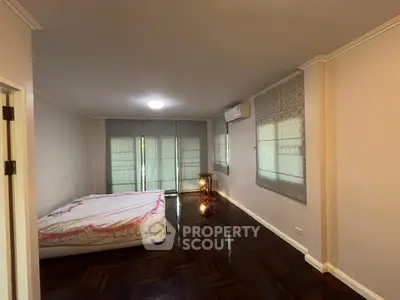 Spacious bedroom with wooden flooring and large windows for natural light